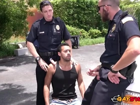 Gay police officers are aided by a prisoner in a threesome with oral sex and analingus in an alley.